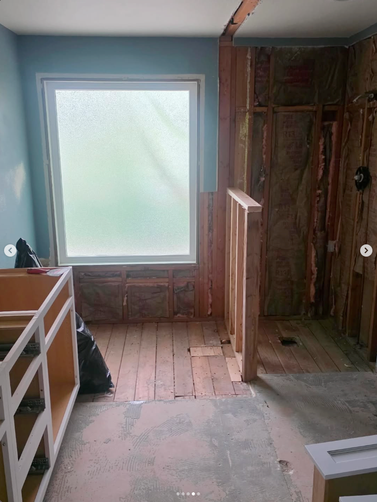 The same bathroom during demolition, with exposed framing beside its frosted window.
